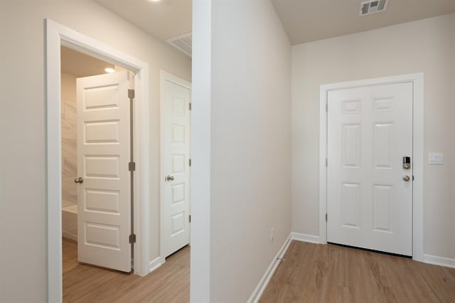 corridor with visible vents, light wood finished floors, and baseboards