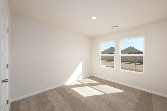 empty room with carpet floors, visible vents, and baseboards
