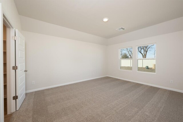 carpeted empty room featuring baseboards and visible vents