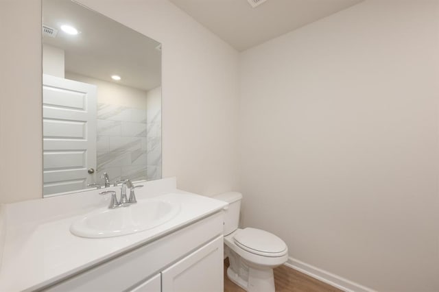 full bathroom with wood finished floors, vanity, baseboards, toilet, and recessed lighting
