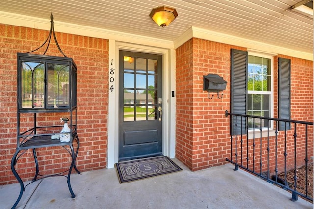 entrance to property featuring brick siding and covered porch
