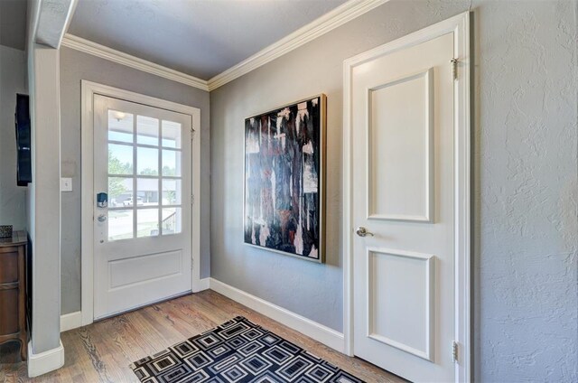 doorway to outside with baseboards, ornamental molding, and light wood finished floors