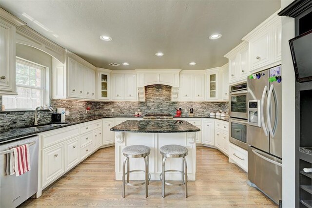 kitchen featuring decorative backsplash, a kitchen breakfast bar, a center island, a sink, and stainless steel appliances