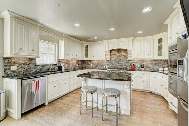 kitchen with a sink, decorative backsplash, appliances with stainless steel finishes, and a breakfast bar area