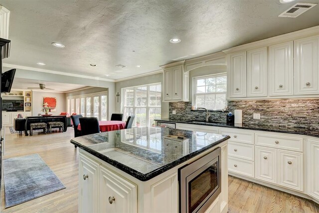 kitchen with visible vents, open floor plan, stainless steel microwave, tasteful backsplash, and a sink