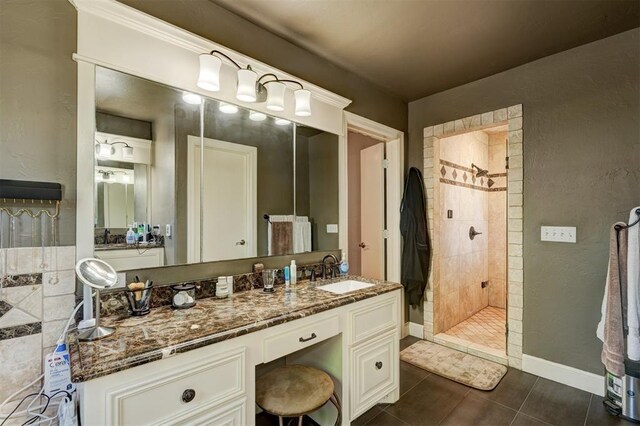 full bath with vanity, baseboards, and a tile shower