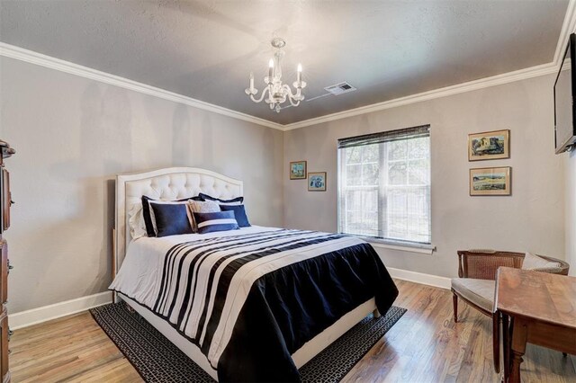 bedroom with visible vents, crown molding, baseboards, light wood finished floors, and an inviting chandelier