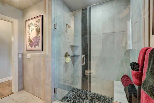 bathroom featuring tile walls, tile patterned flooring, and a shower stall