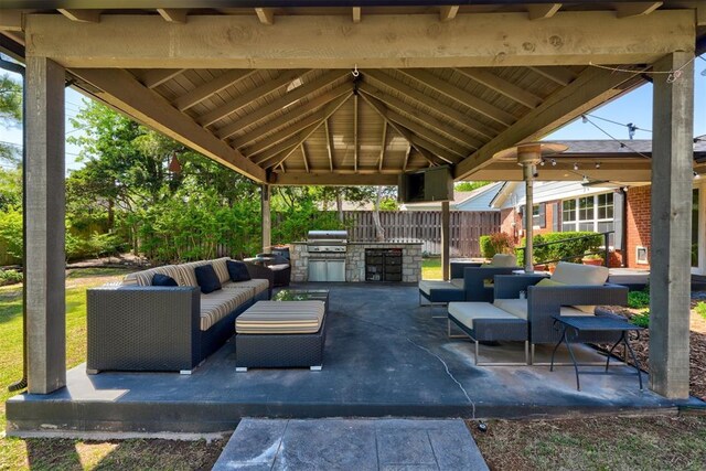 view of patio with fence, grilling area, an outdoor hangout area, exterior kitchen, and a gazebo