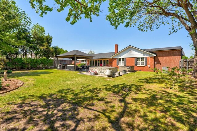 back of house with fence, a patio, a gazebo, brick siding, and a lawn