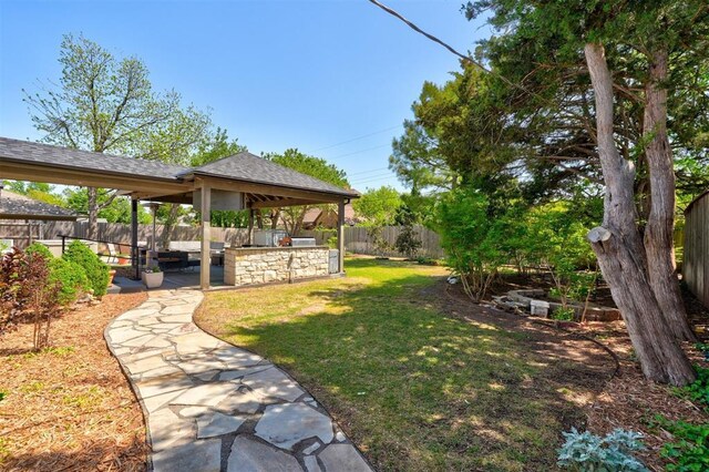 view of yard with a patio, an outdoor kitchen, a gazebo, and a fenced backyard