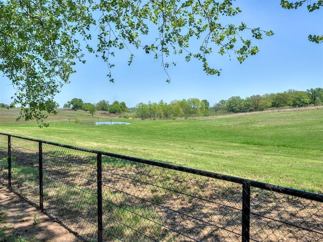 view of yard featuring fence, a water view, and a rural view