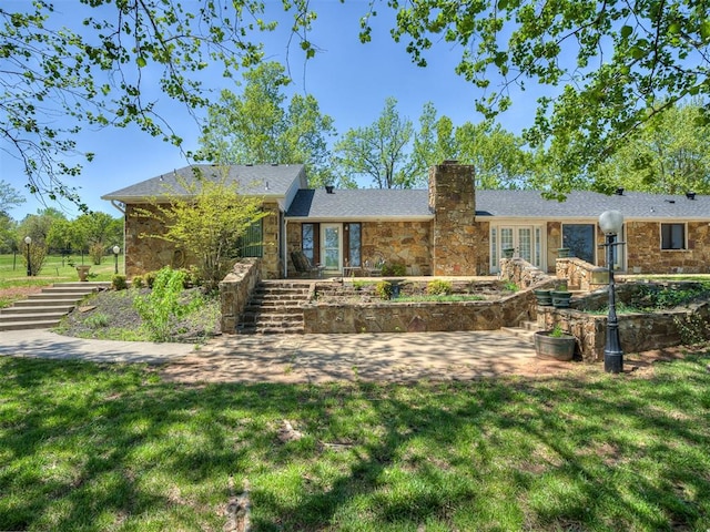 rear view of property featuring a lawn, stone siding, stairway, and a chimney