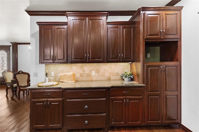 kitchen with backsplash, dark wood finished floors, light stone counters, and decorative columns