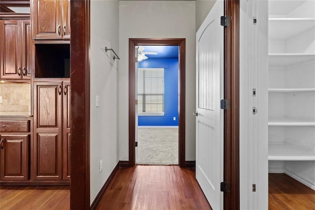 corridor featuring built in features, baseboards, and dark wood-style flooring