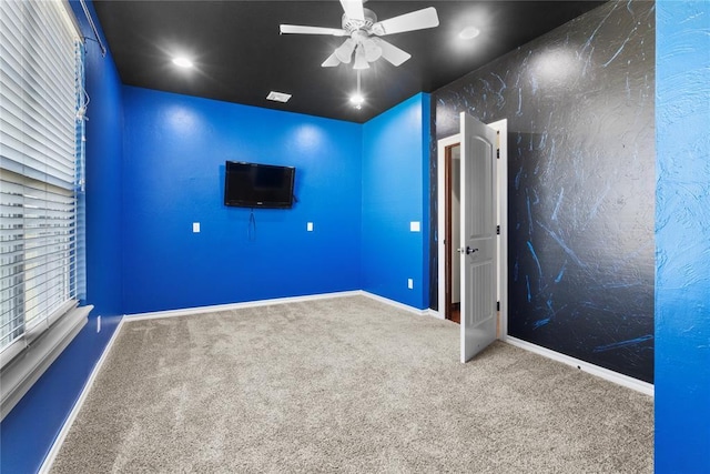 carpeted empty room with ceiling fan and baseboards