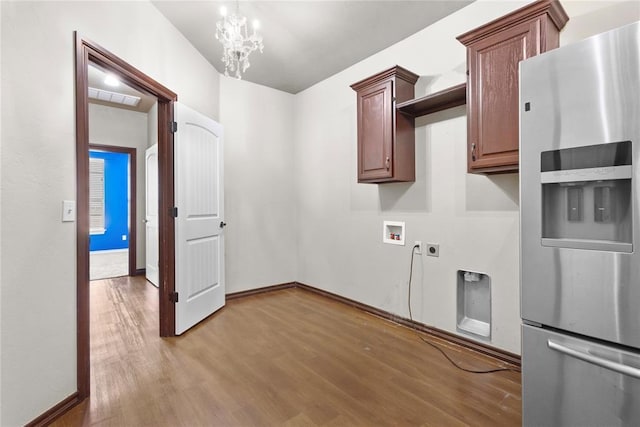 clothes washing area featuring electric dryer hookup, a notable chandelier, hookup for a washing machine, and light wood-type flooring