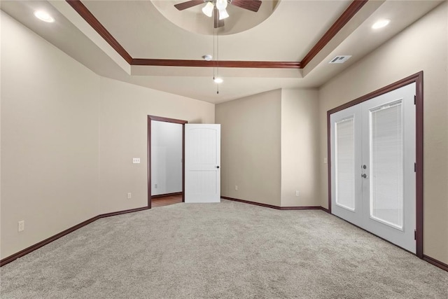unfurnished bedroom featuring a tray ceiling, carpet floors, visible vents, and ornamental molding