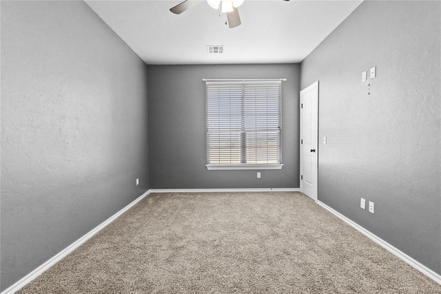 spare room featuring baseboards, visible vents, carpet, and ceiling fan