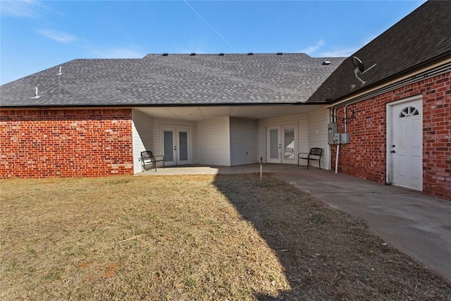 back of property with brick siding, roof with shingles, and french doors
