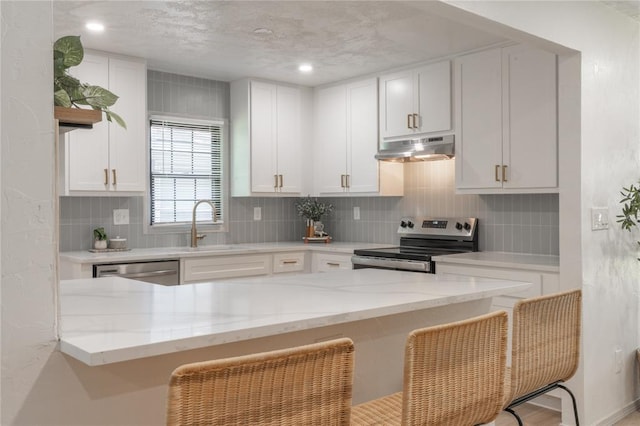 3224 NW 47th St, Oklahoma City, OK 73112 - kitchen with a sink, under cabinet range hood, a breakfast bar, white cabinetry, and appliances with stainless steel finishes
