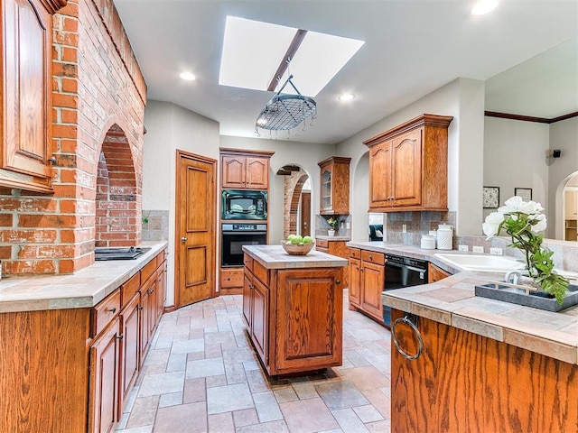 3401 Kentucky Way, Edmond, OK 73034 - kitchen featuring stone tile floors, a skylight, decorative backsplash, and black appliances