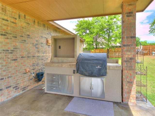 view of patio featuring fence, a grill, and exterior kitchen