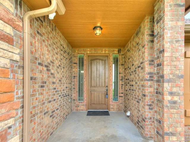 view of exterior entry with covered porch and brick siding