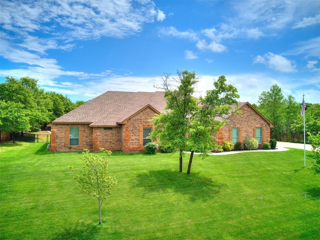 single story home featuring a shingled roof, a front lawn, and brick siding