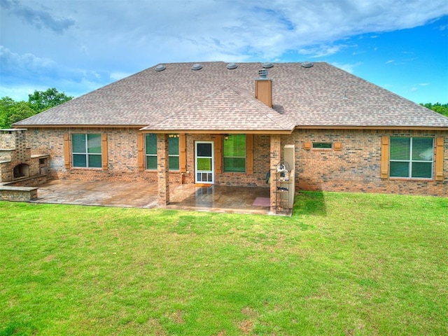 rear view of property featuring brick siding, roof with shingles, a patio area, and a yard