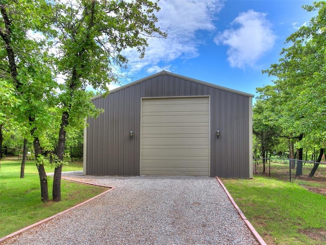 detached garage featuring fence and gravel driveway