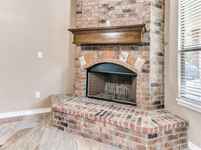 room details featuring a fireplace with raised hearth and baseboards