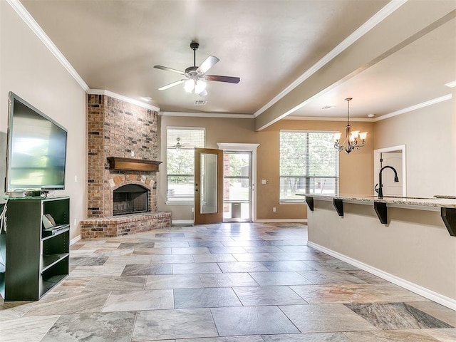 unfurnished living room featuring baseboards, ornamental molding, ceiling fan with notable chandelier, and a fireplace