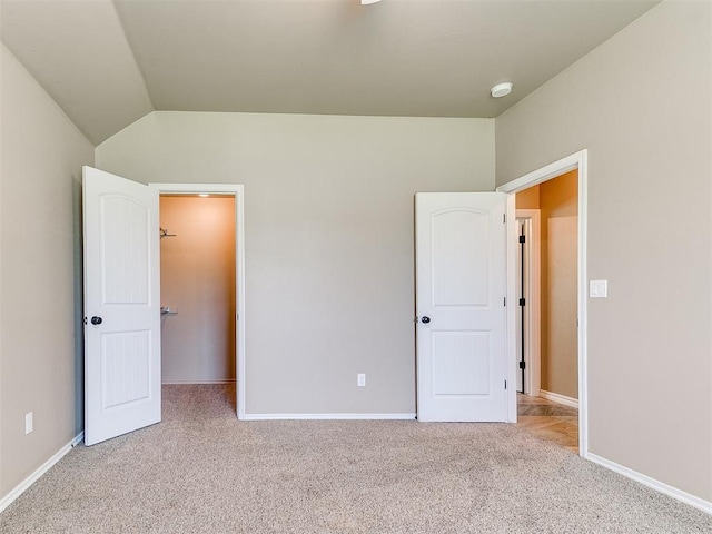 unfurnished bedroom with carpet flooring, baseboards, and lofted ceiling