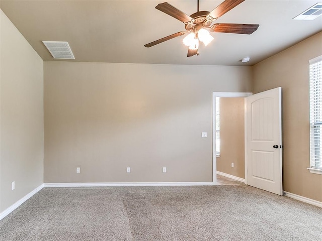 carpeted empty room with visible vents, a ceiling fan, and baseboards
