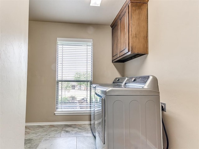 washroom with cabinet space, baseboards, washing machine and dryer, and plenty of natural light