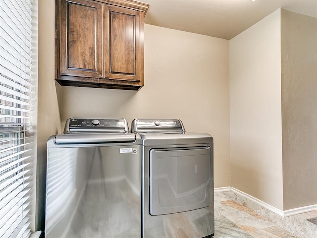 clothes washing area with baseboards, cabinet space, and washer and clothes dryer