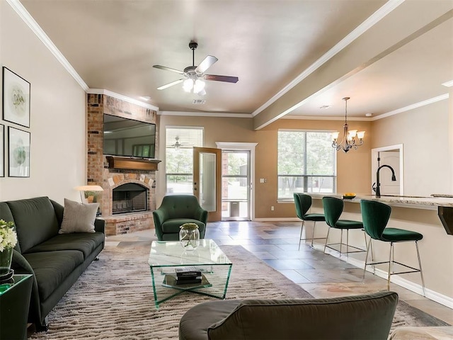 living room with a brick fireplace, baseboards, crown molding, and ceiling fan with notable chandelier