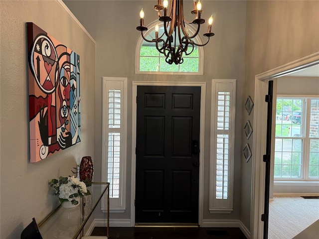 entrance foyer featuring baseboards, a chandelier, and a towering ceiling