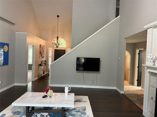 living area with an inviting chandelier, baseboards, wood finished floors, and high vaulted ceiling