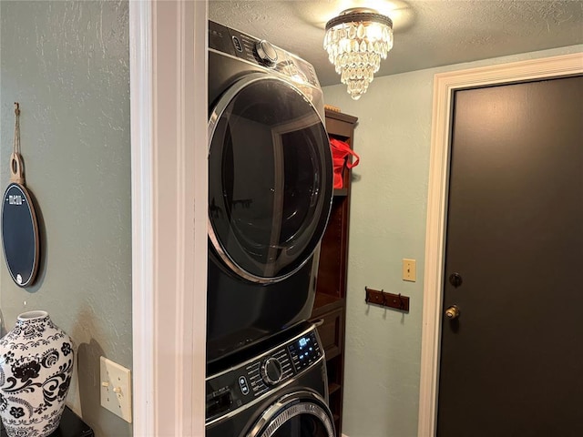 laundry room featuring laundry area, a chandelier, and stacked washer / dryer