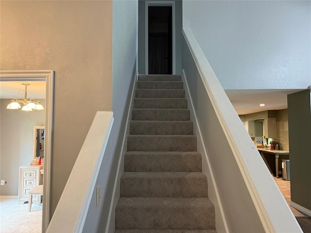 staircase with baseboards and a chandelier