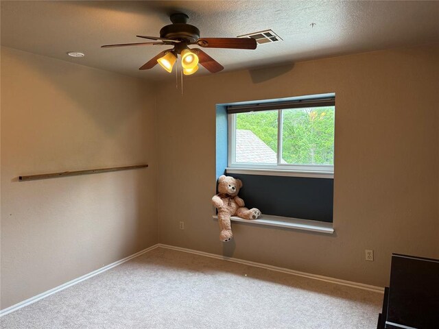 carpeted empty room with visible vents, baseboards, and ceiling fan