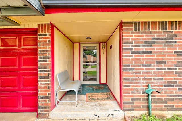 view of exterior entry featuring brick siding and a garage