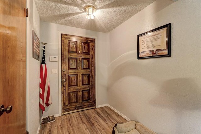 foyer featuring baseboards, a textured ceiling, and wood finished floors
