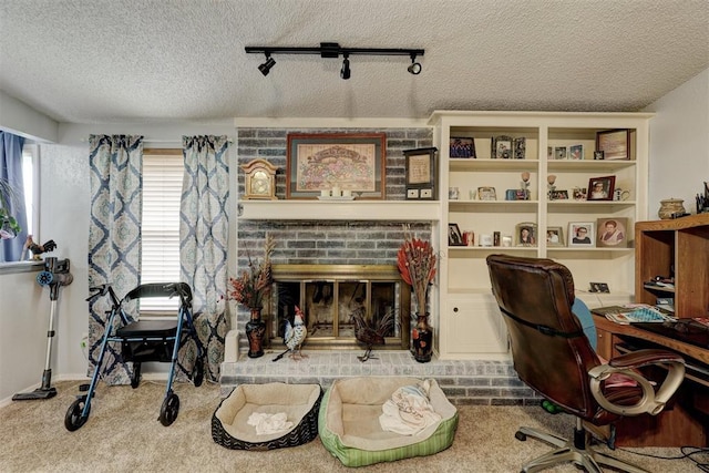 office area featuring carpet flooring, a textured ceiling, a brick fireplace, and rail lighting