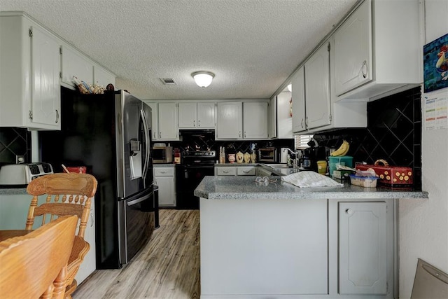 kitchen with a textured ceiling, a peninsula, and black / electric stove
