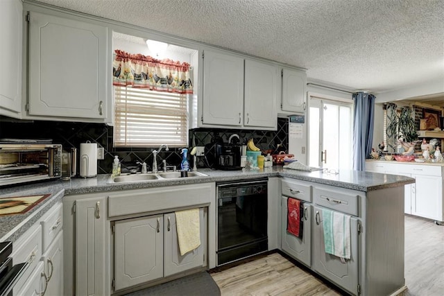 kitchen featuring decorative backsplash, a textured ceiling, a sink, a peninsula, and black dishwasher