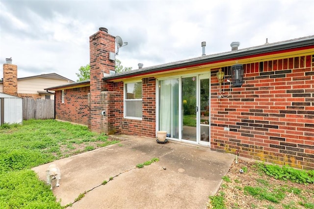 back of property with a patio, a chimney, fence, and brick siding