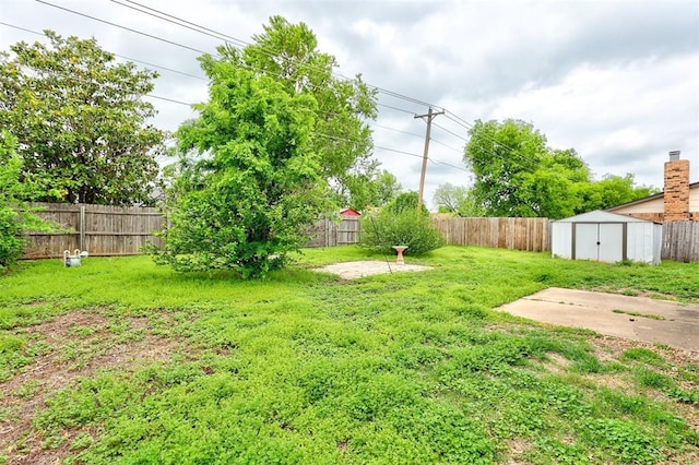 view of yard with a fenced backyard, a shed, and an outbuilding